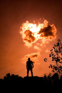 Silhouette man standing on field against sky during sunset