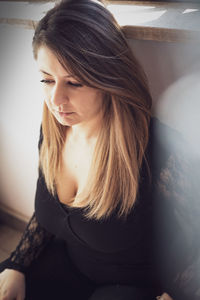 Young woman looking down while sitting at home