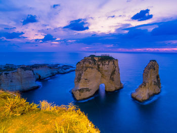 Rock formations by sea against blue sky