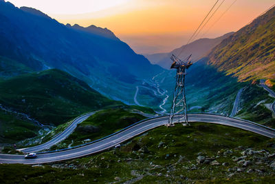 Electricity pylon on mountain against sky during sunset