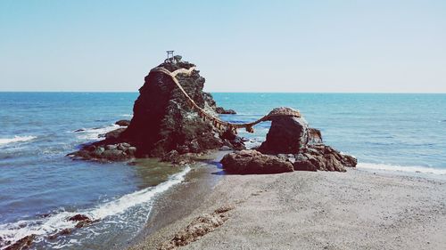 Rock formation on beach against clear sky