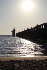 Silhouette man standing on beach against clear sky during sunset