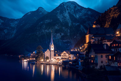 Illuminated buildings by city against sky at dusk
