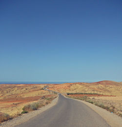Road on desert against clear blue sky