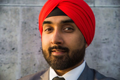 Close-up portrait of businessman wearing turban standing against wall