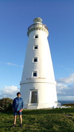 Low angle view of man standing on lighthouse against blue sky