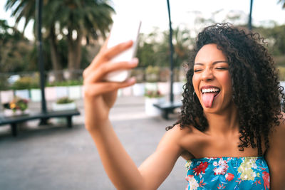 Portrait of smiling young woman using mobile phone outdoors