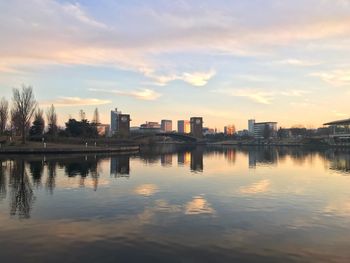 Reflection of buildings in lake against sky during sunset