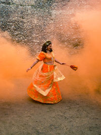 Smiling young bride dancing against wall