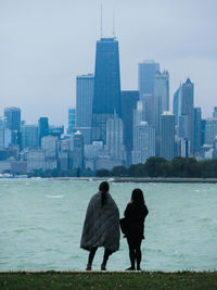 Rear view of two people in front of sea