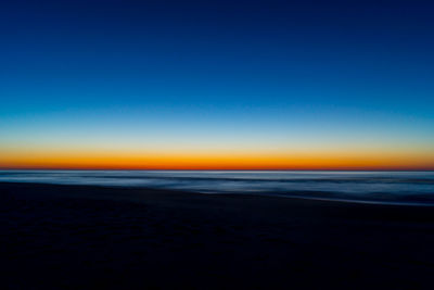 Scenic view of beach against clear blue sky