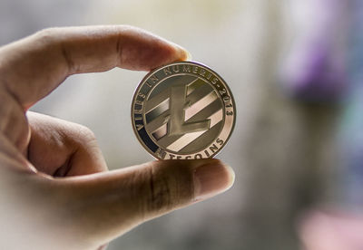 Close-up of hand holding cigarette against blurred background