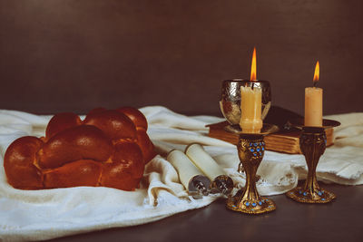 Food and drink with burning candles on table against wall