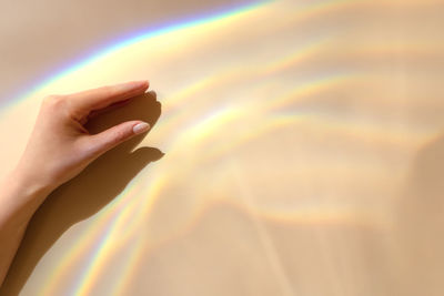 Female hand with sun refraction on beige background. overlay mode. caustic effect of light