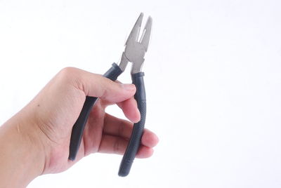 Close-up of hand holding ring over white background