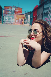 Close-up young woman wearing sunglasses while lying at playground during sunny day