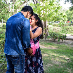 Indian couple posing for maternity baby shoot. the couple is posing in a lawn with green grass