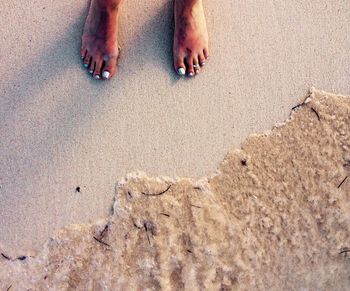 Low section of woman standing on sand at beach