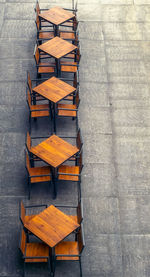 High angle view of empty chairs with tables arranged on street at sidewalk cafe