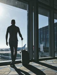 Rear view of man standing by window