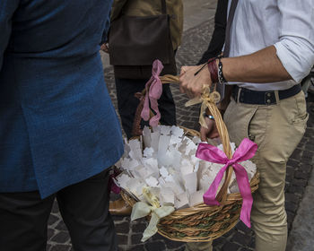 Midsection of man holding umbrella while standing by wicker basket