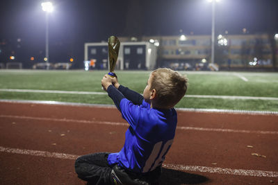 Young soccer player in blue jersey with ten number raising a trophy after the winning goal