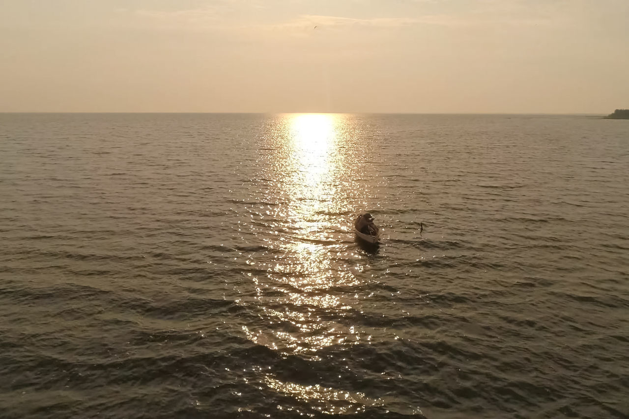 MAN SWIMMING IN SEA DURING SUNSET