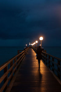 Pier over sea against sky at night