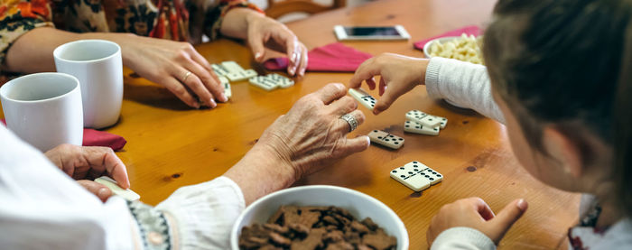 Close-up of family playing dominoes while having food at table