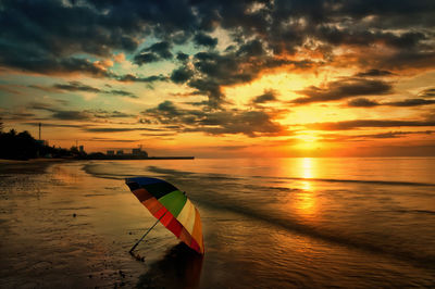 Multi colored umbrella on scenic beach against sky during sunset