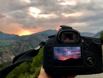 Close-up of camera photographing against sky during sunset