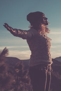 Rear view of woman standing against sky during sunset