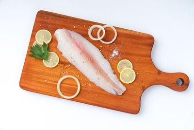 High angle view of bread and knife on cutting board against white background