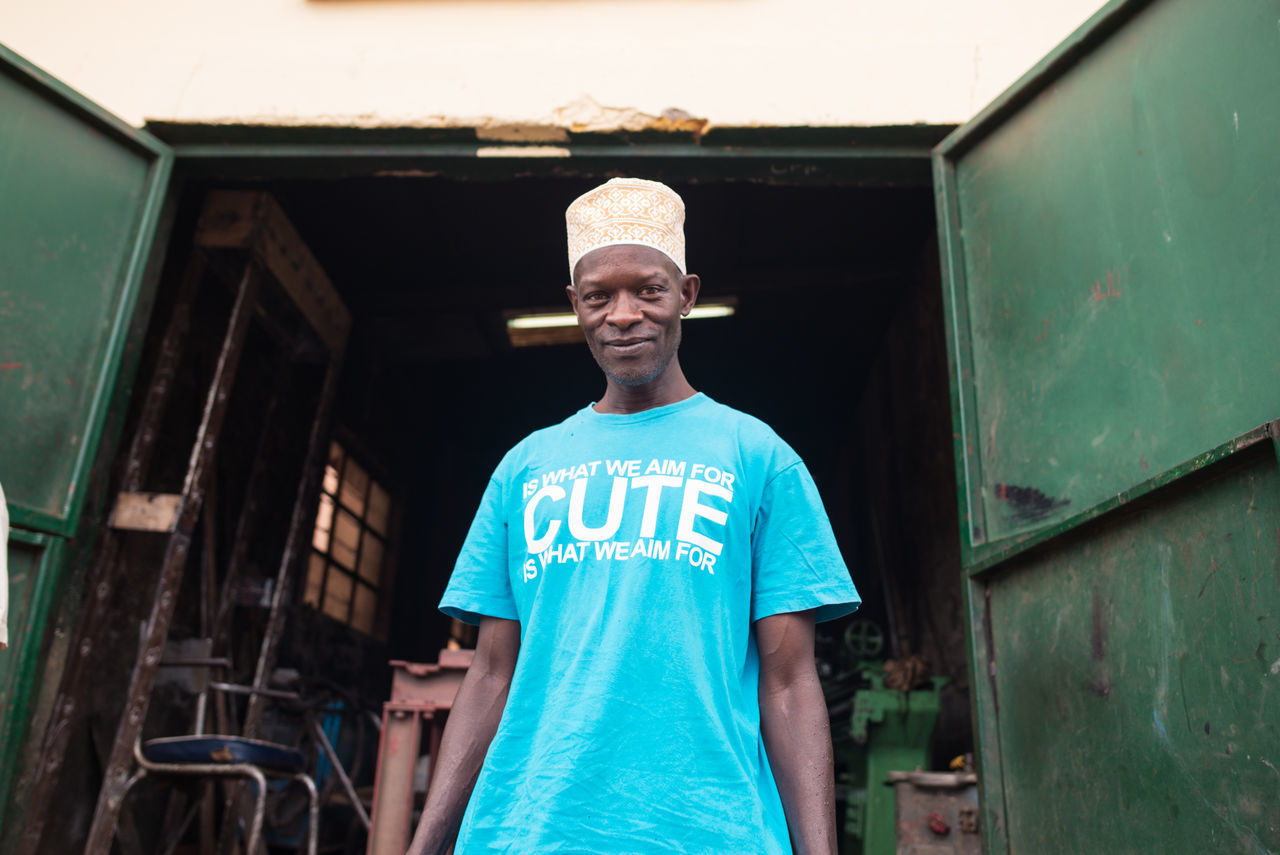 Ruanda, africa - december 14, 2019: positive african american male in casual wear standing in street near workshop looking at camera
