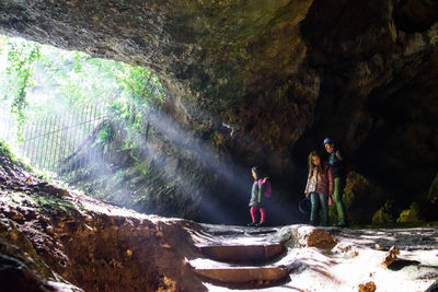 A family in a cave entrance with crepuscular rays