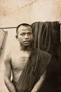 Portrait of shirtless man standing against wall