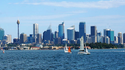 Boats in sea against skyscrapers in city