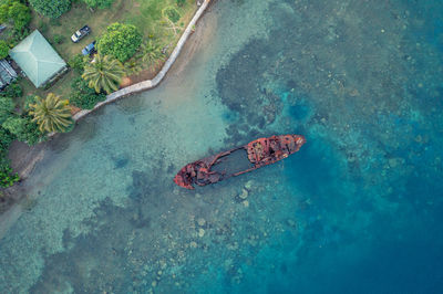 Top view of rusty wrecked boat in turquoise water near tropical shore. drone photo. sanma, vanuatu