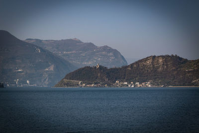 Scenic view of sea by mountains against clear sky