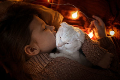 Sleeping baby girl hugging a white cat with ears, a cozy childhood and home environment, a pet. 