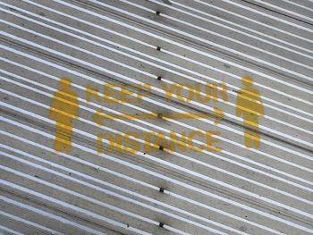 Photograph above coronavirus information  on a metal walkway. text  reads keep your distance. 