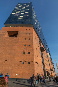 Low angle view of people walking in front of skyscraper