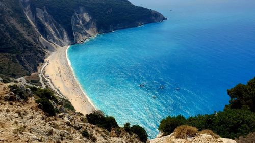 High angle view of sea by mountains against sky