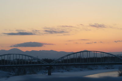 Bridge over mountains against sky during sunset