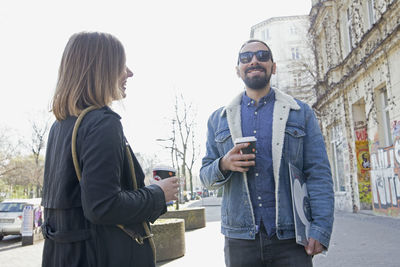 Young couple drinking coffee on sidewalk