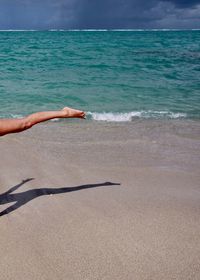 Low section of woman at beach during sunny day