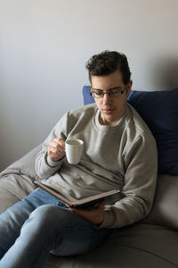 Portrait of young man sitting on sofa at home