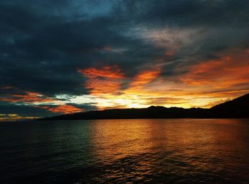 Scenic view of sea against dramatic sky during sunset