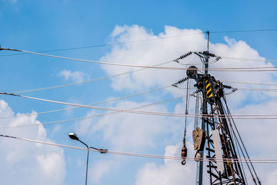 Low angle view of electricity pylon against blue sky