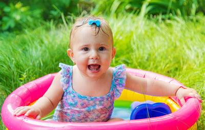 Portrait of smiling cute baby girl sitting in wading pool